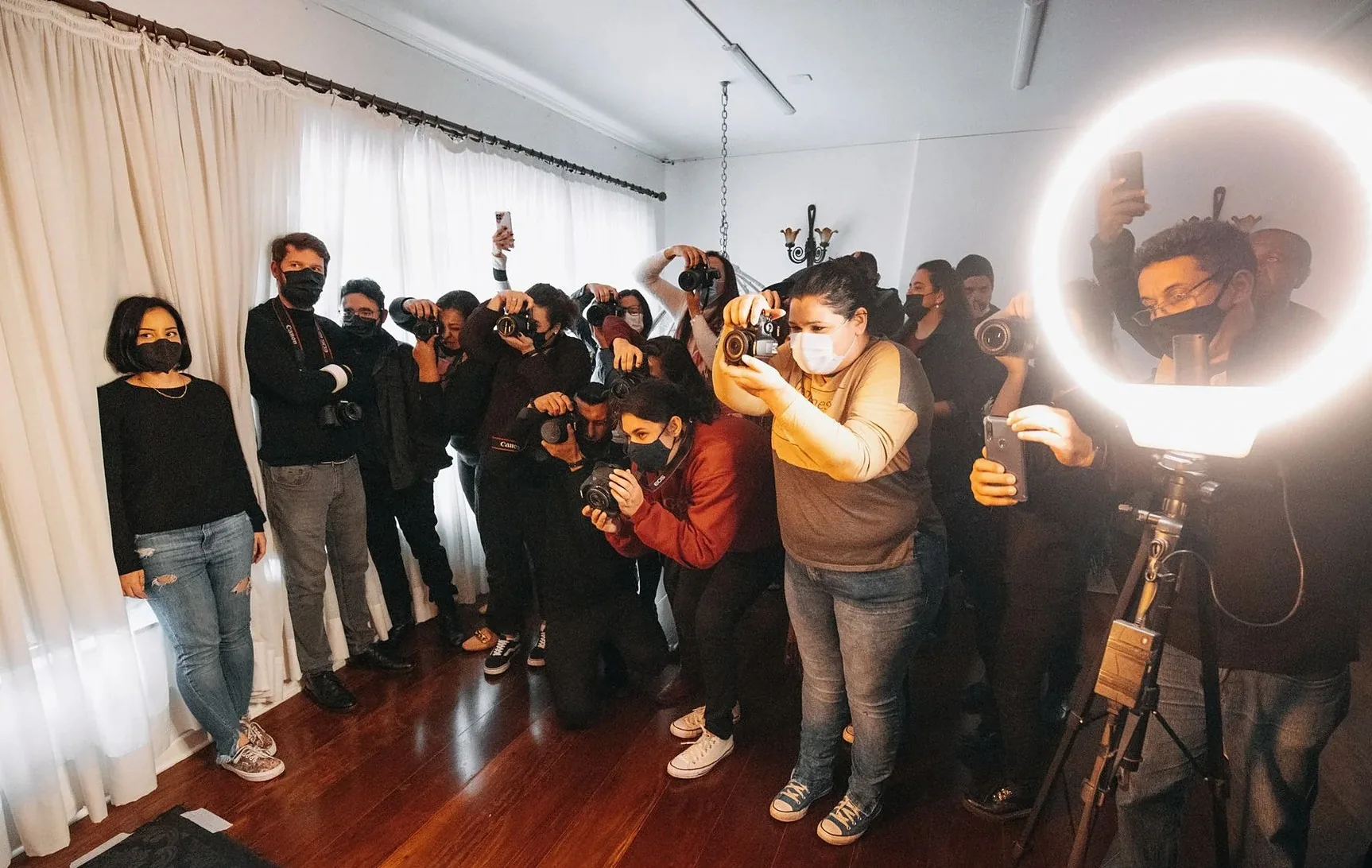 Group of people in a photography workshop wearing facemasks indoors, focused on a session.